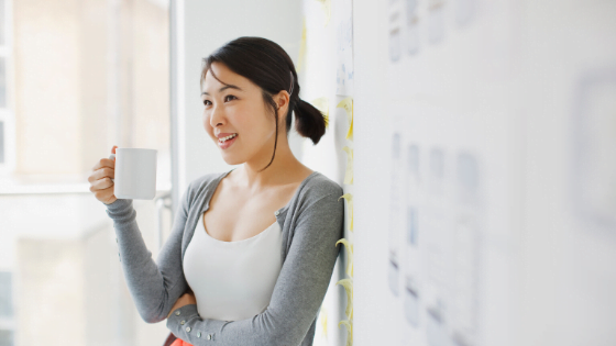 Women with mug leaning against whiteboard